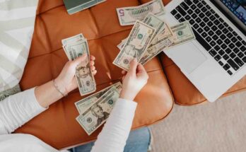 Person counting cash near laptop while working online from home
