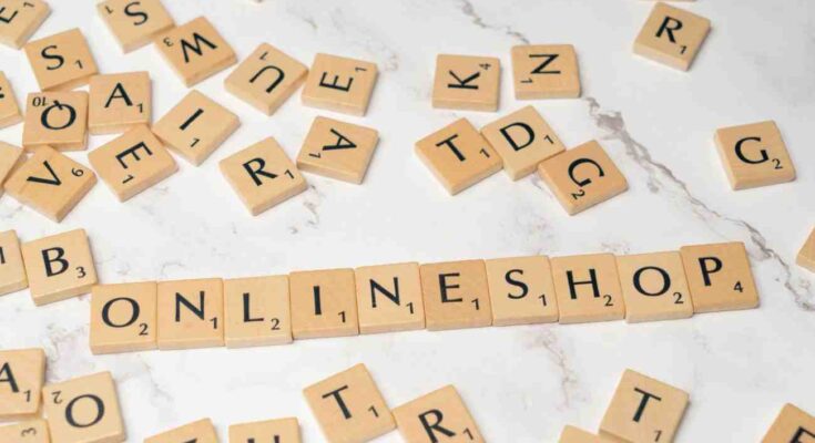 Wooden letter tiles scattered across a light marble surface, with the word'' online Shop'' spelled out in a center