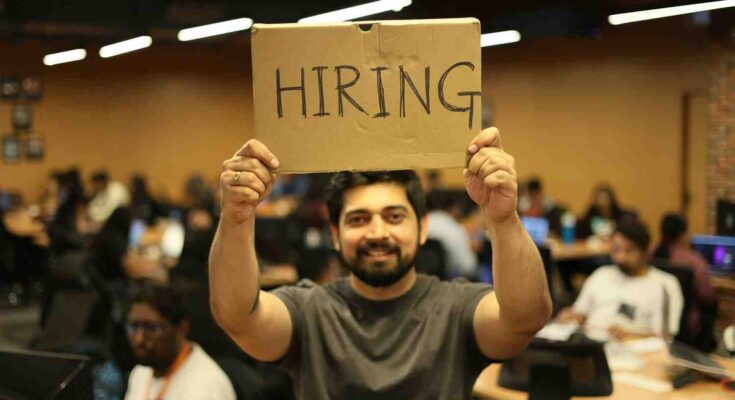 Person holding a hiring sign representing companies recruiting professionals with in- demand remote work skills